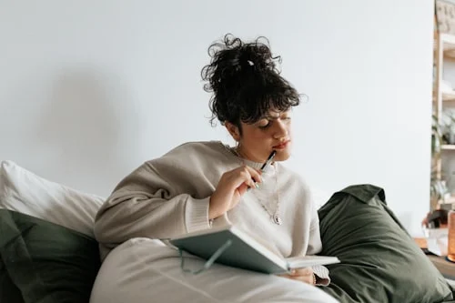 Woman journaling at a quiet table practicing the self-care skill of saying no and setting personal boundaries
