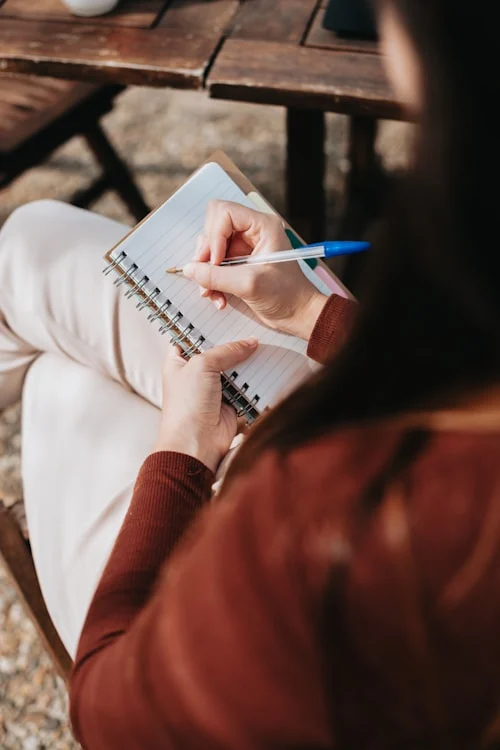 Hands writing emotional journaling prompts for self-awareness