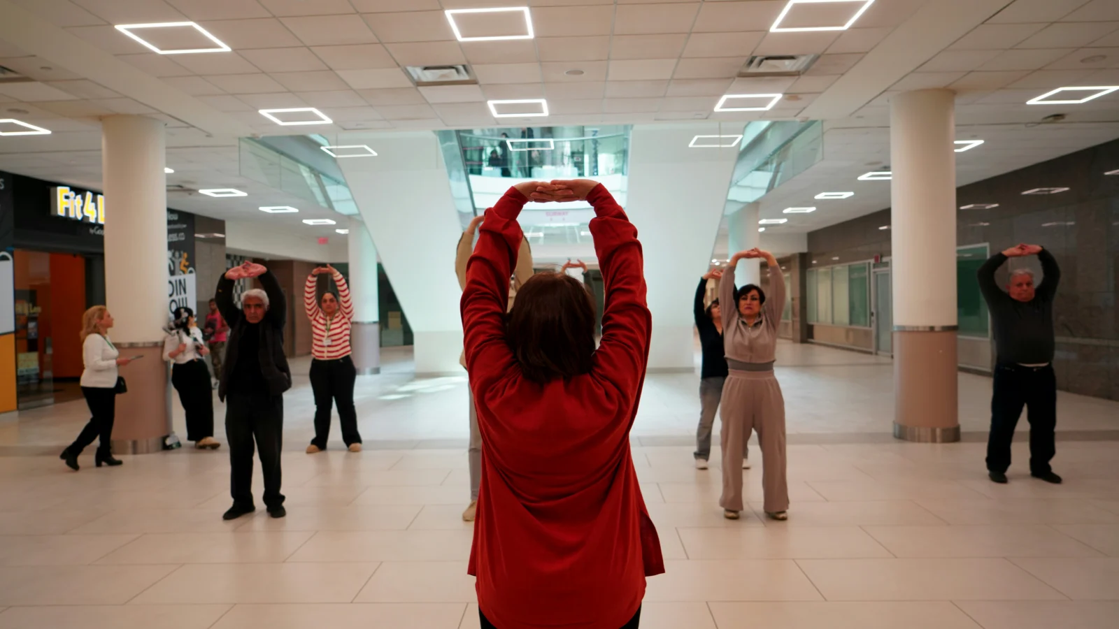 Older adults practicing beginner tai chi movements together in a group class