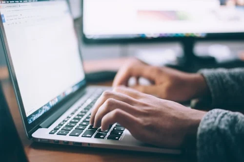 Professional typing a business email on laptop — professional email writing tips for workplace communication
