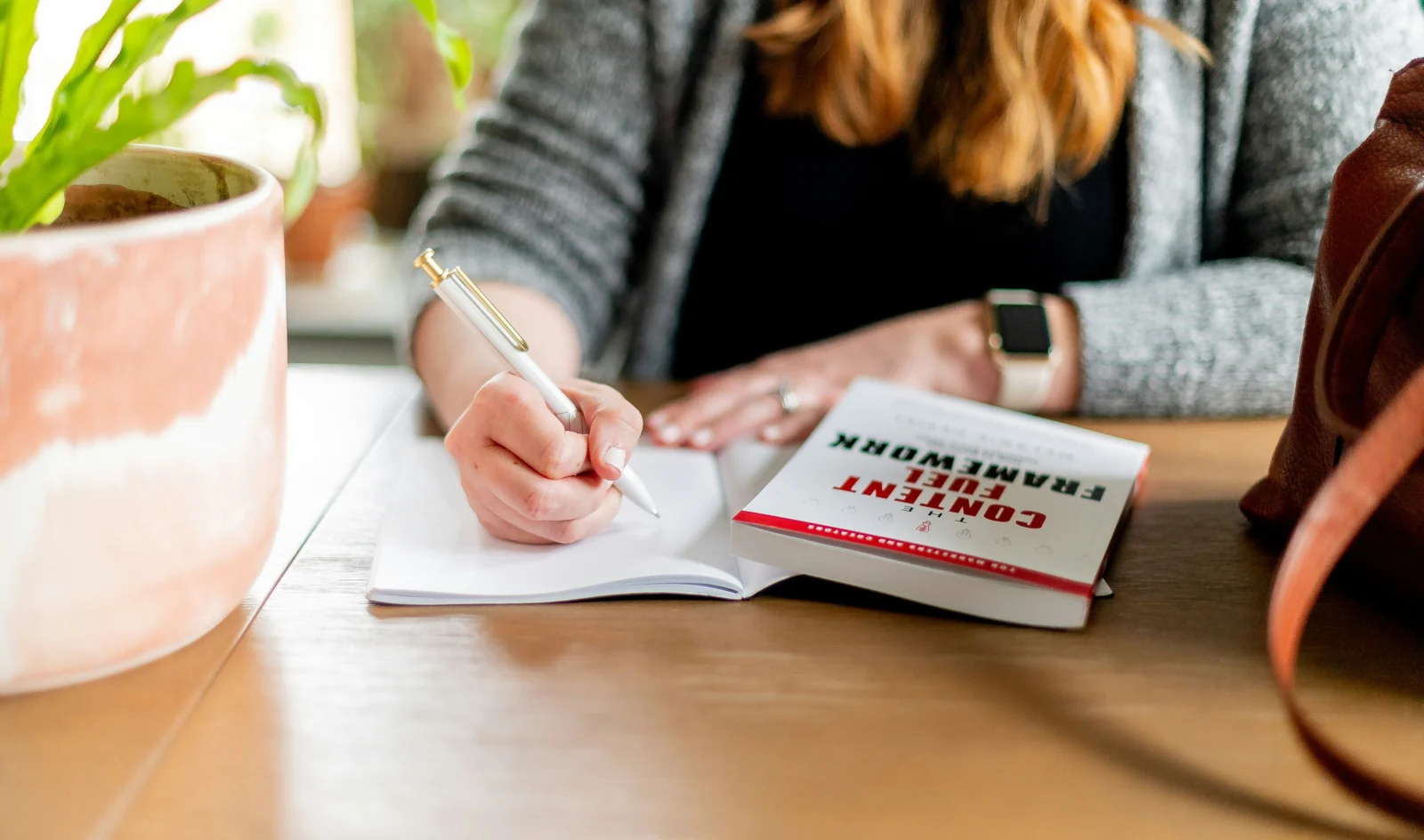 Woman writing SMART goals and action steps in a notebook at her desk