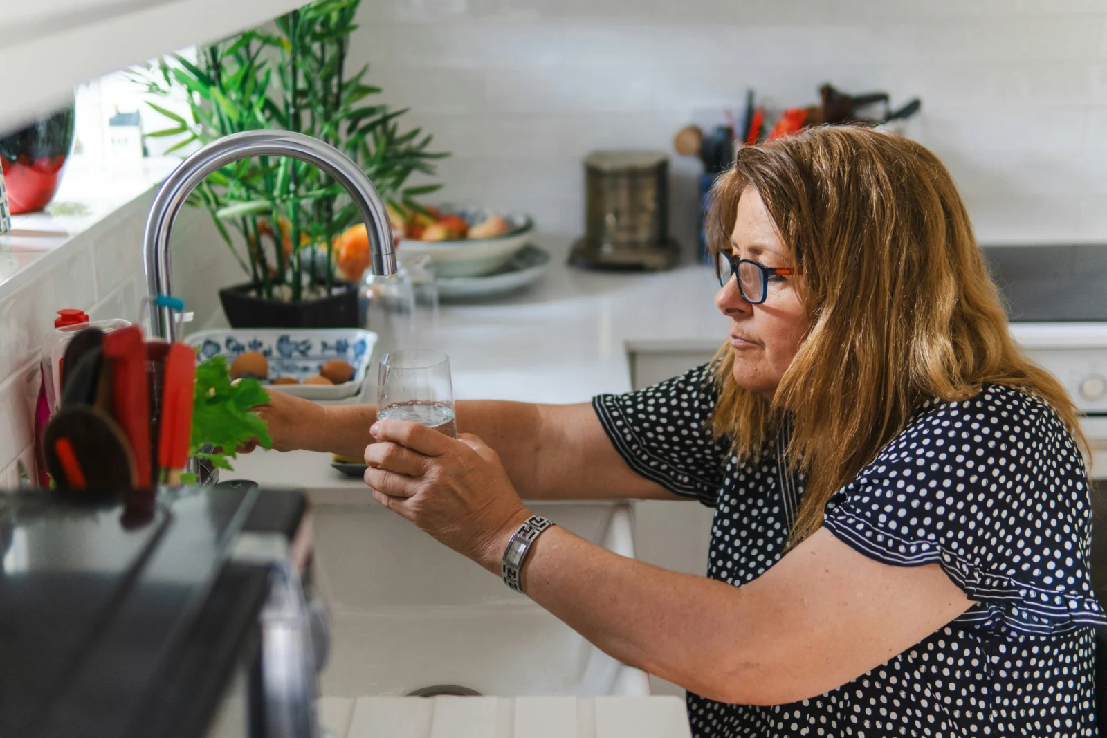 Woman drinking water at home while reconsidering common hydration myths