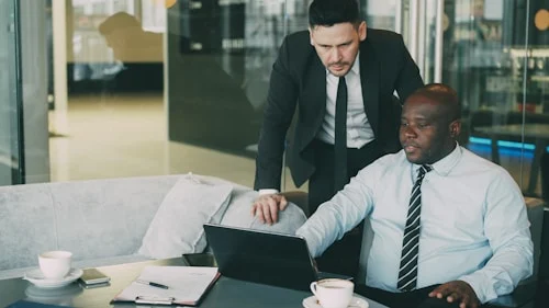 Two colleagues reviewing feedback examples together during a workplace conversation